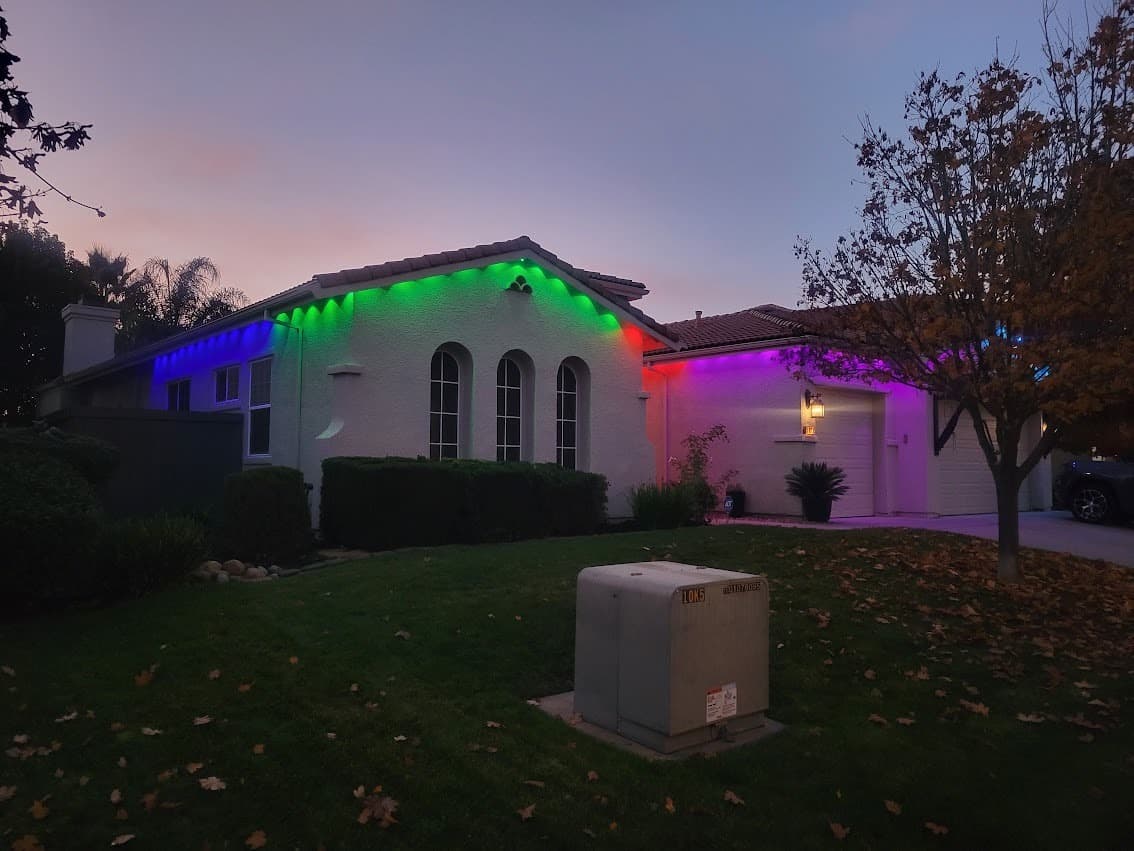 Exterior accent lighting washing the eaves and stonework of a home at dusk after installation