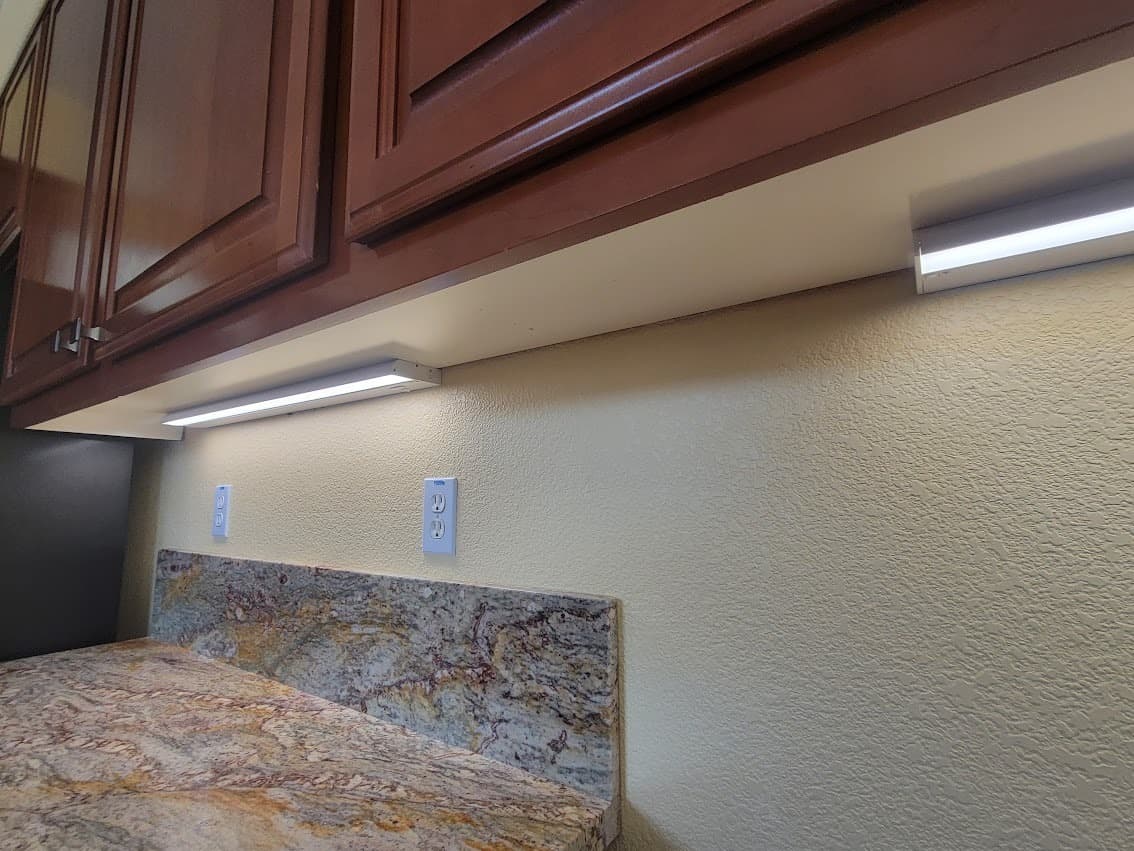 LED under-cabinet lighting strips installed beneath kitchen upper cabinets, lighting the countertop