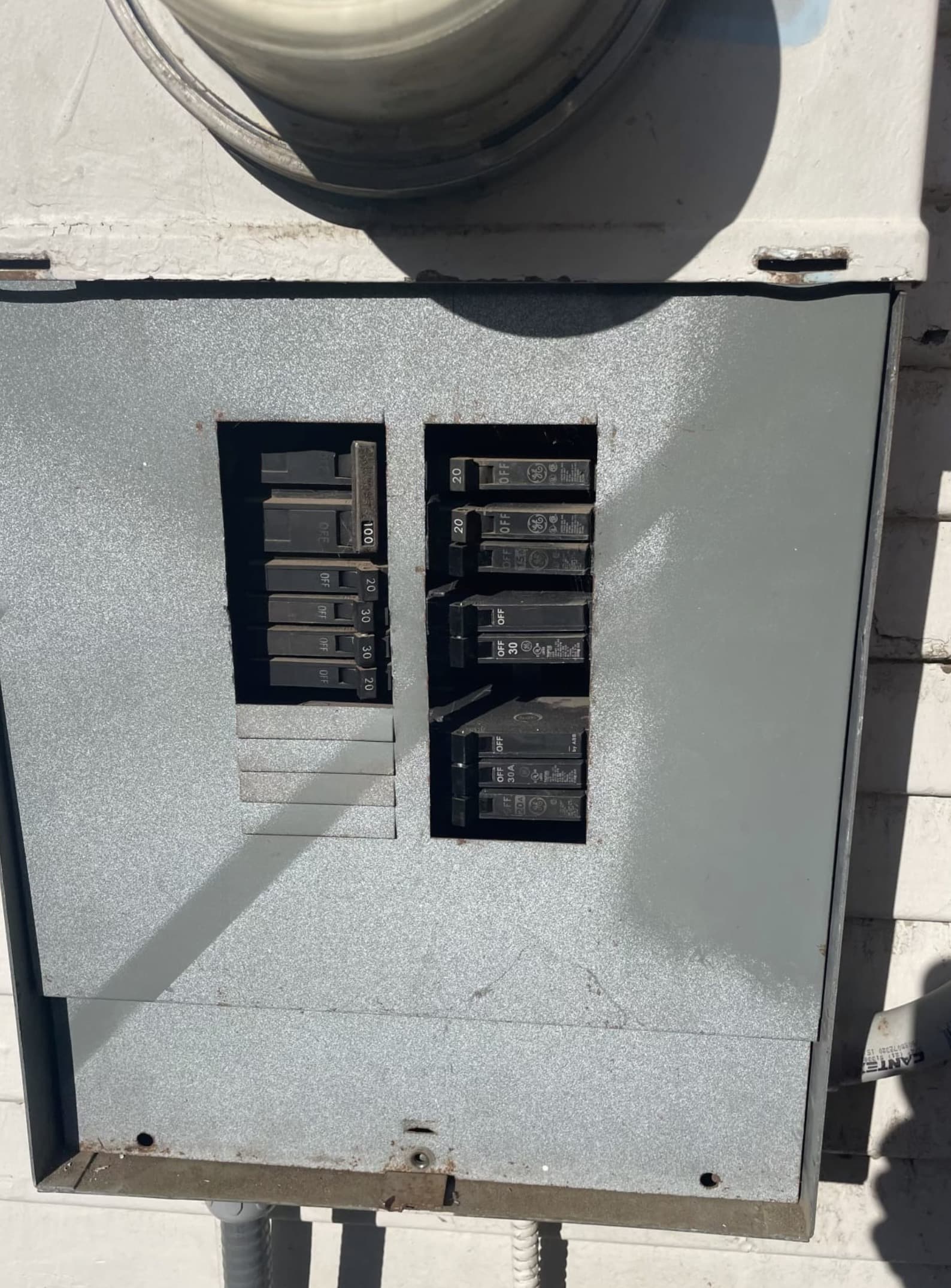 Exterior-mounted main electrical service panel installed on the outside wall of a home with conduit runs to the meter